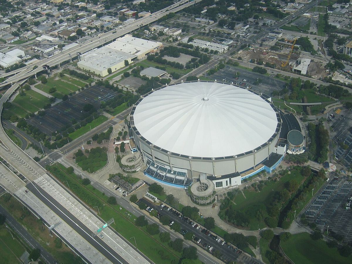 Aerial view of the white domed roof of Tropicana Field surrounded by parking lots, trees and highways in St. Petersburg, Florida
