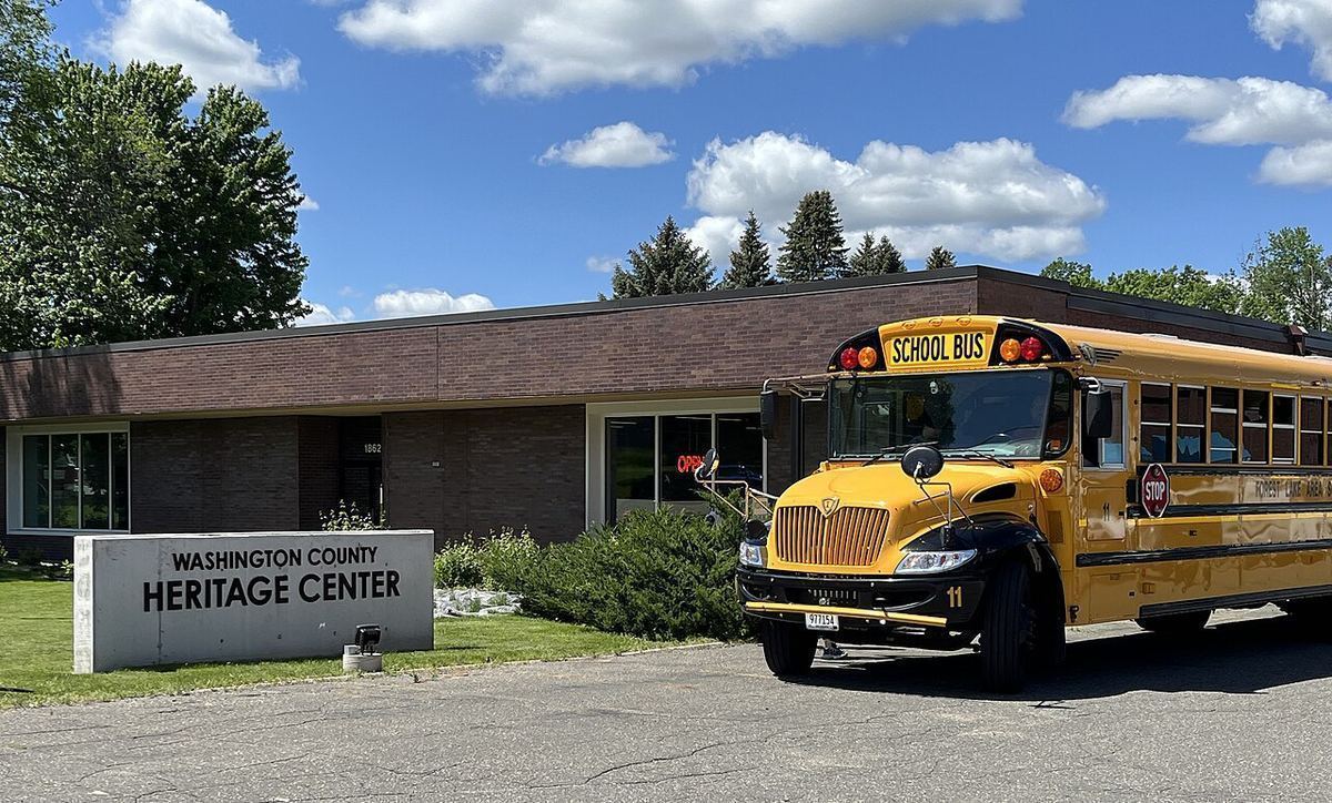 A yellow school bus parked outside the Washington County Heritage Center in Stillwater, Minnesota, under a blue sky